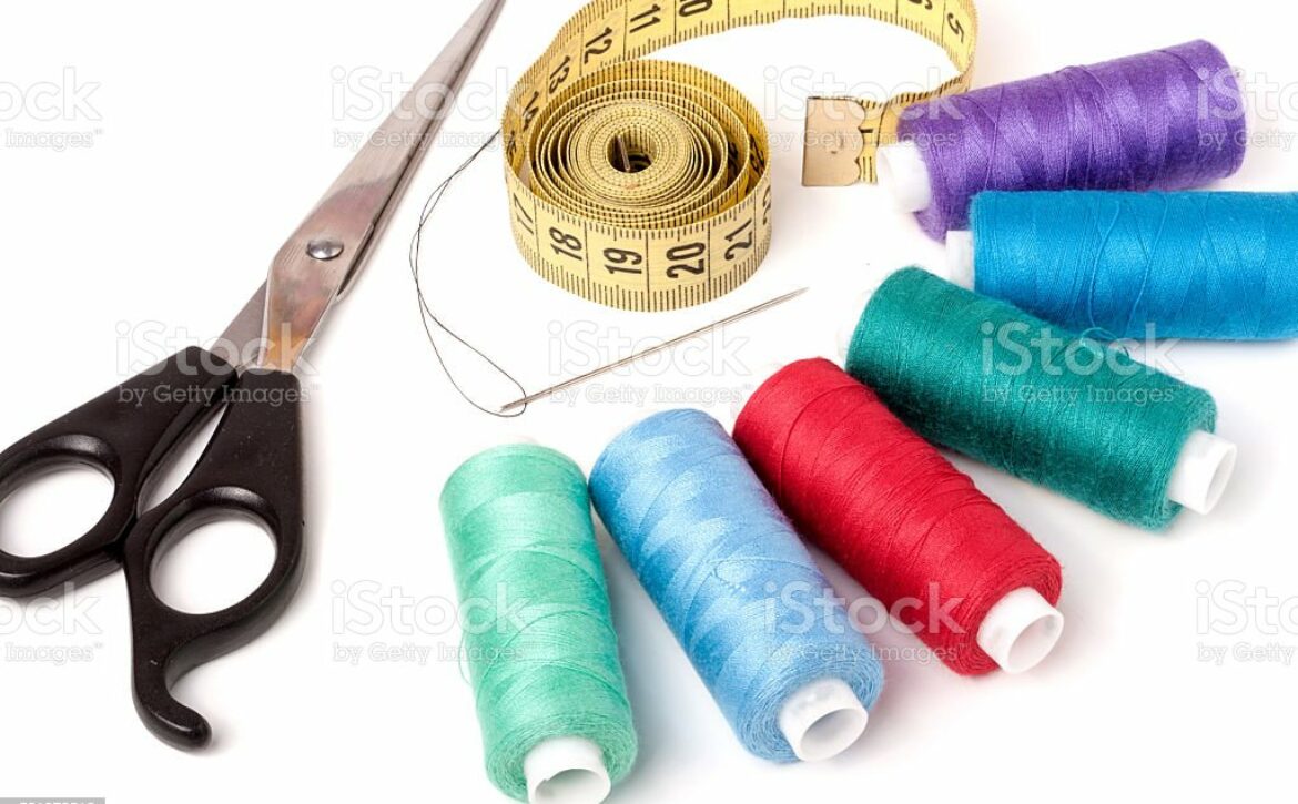 thread sewing needle centimeter scissors on a white background.