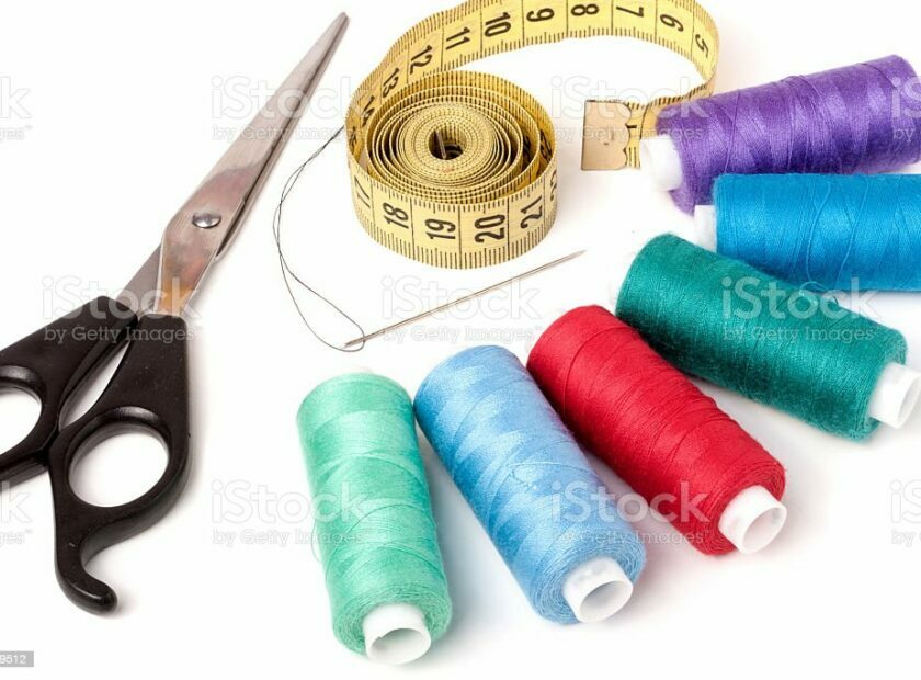 thread sewing needle centimeter scissors on a white background.